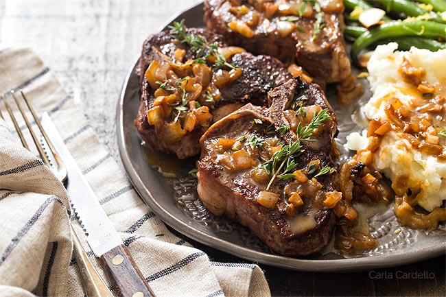 Fried lamb chops on plate with pan sauce