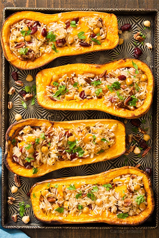 Four stuffed butternut squash halves on a baking sheet