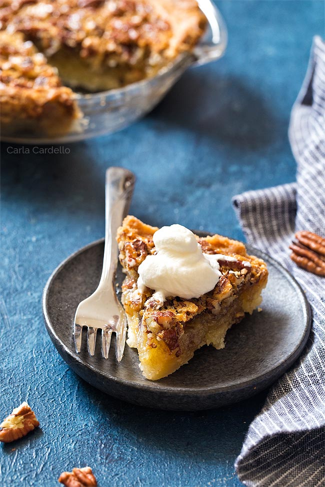 Slice of pecan pie with whipped cream on a plate