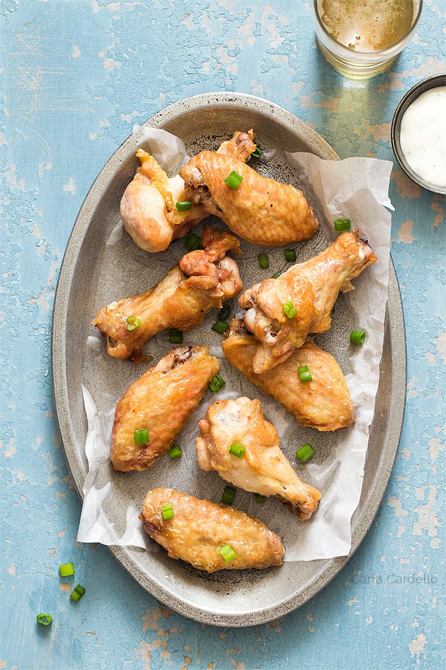 crispy wings on a silver plate with blue background