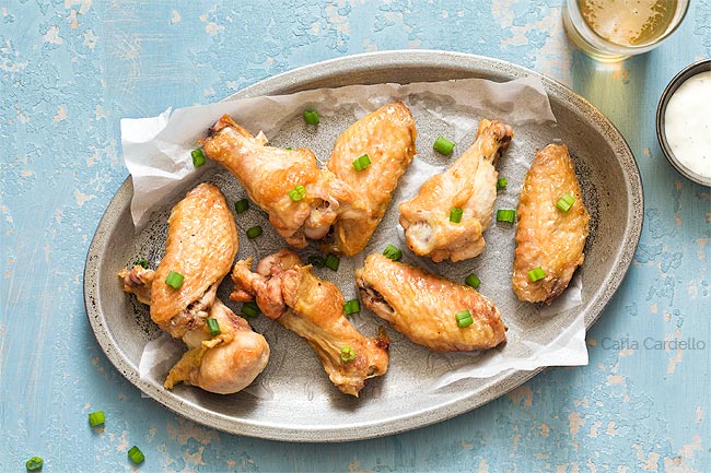 crispy wings on a silver plate with blue background