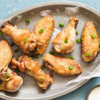 crispy wings on a silver plate with blue background