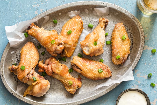 crispy wings on a silver plate with blue background