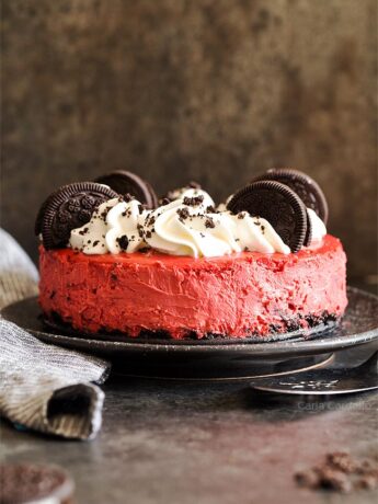 Red Velvet Cheesecake with whipped cream and Oreo cookies on a black plate