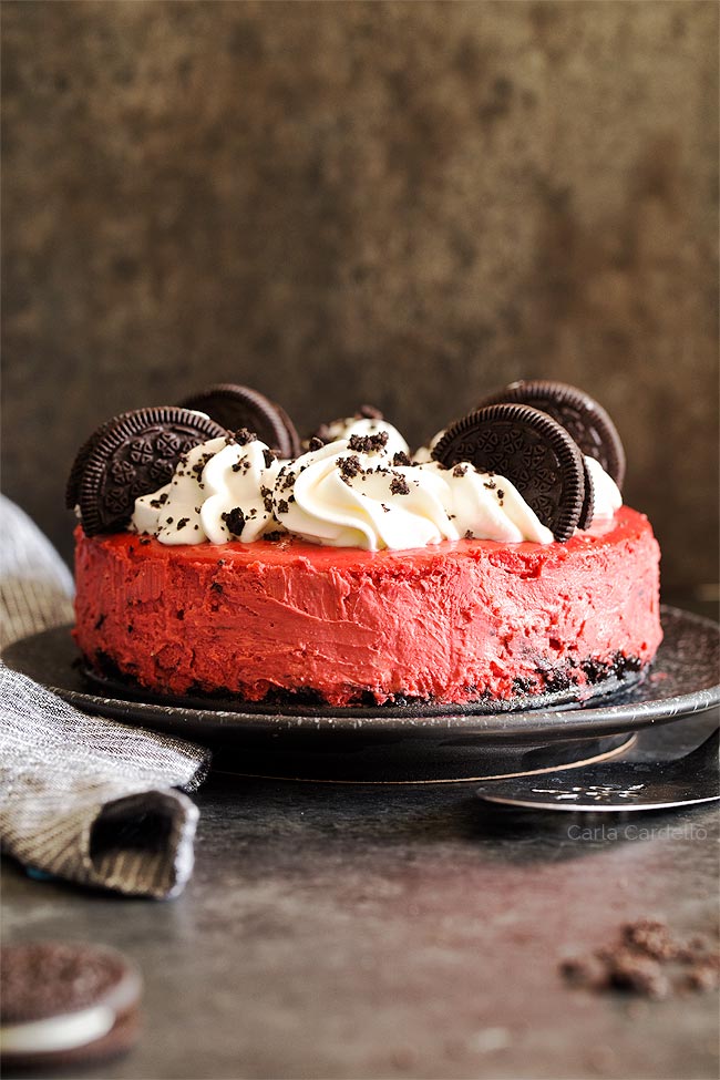 Red Velvet Cheesecake with whipped cream and Oreo cookies on a black plate