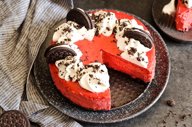 Red Velvet Cheesecake with slice missing on black plate