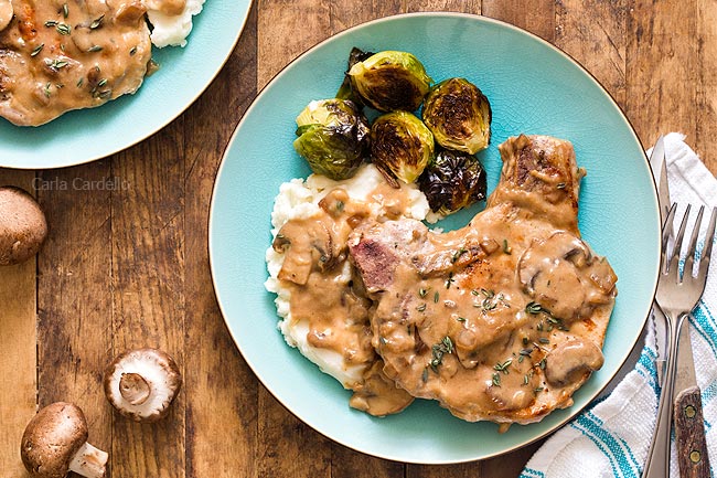 Pork chop with gravy, mashed potatoes, and Brussels sprouts on a blue plate