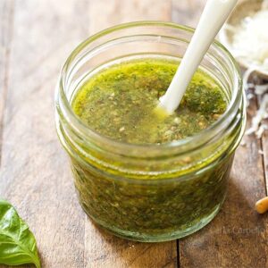Basil pesto in small jar with white spoon