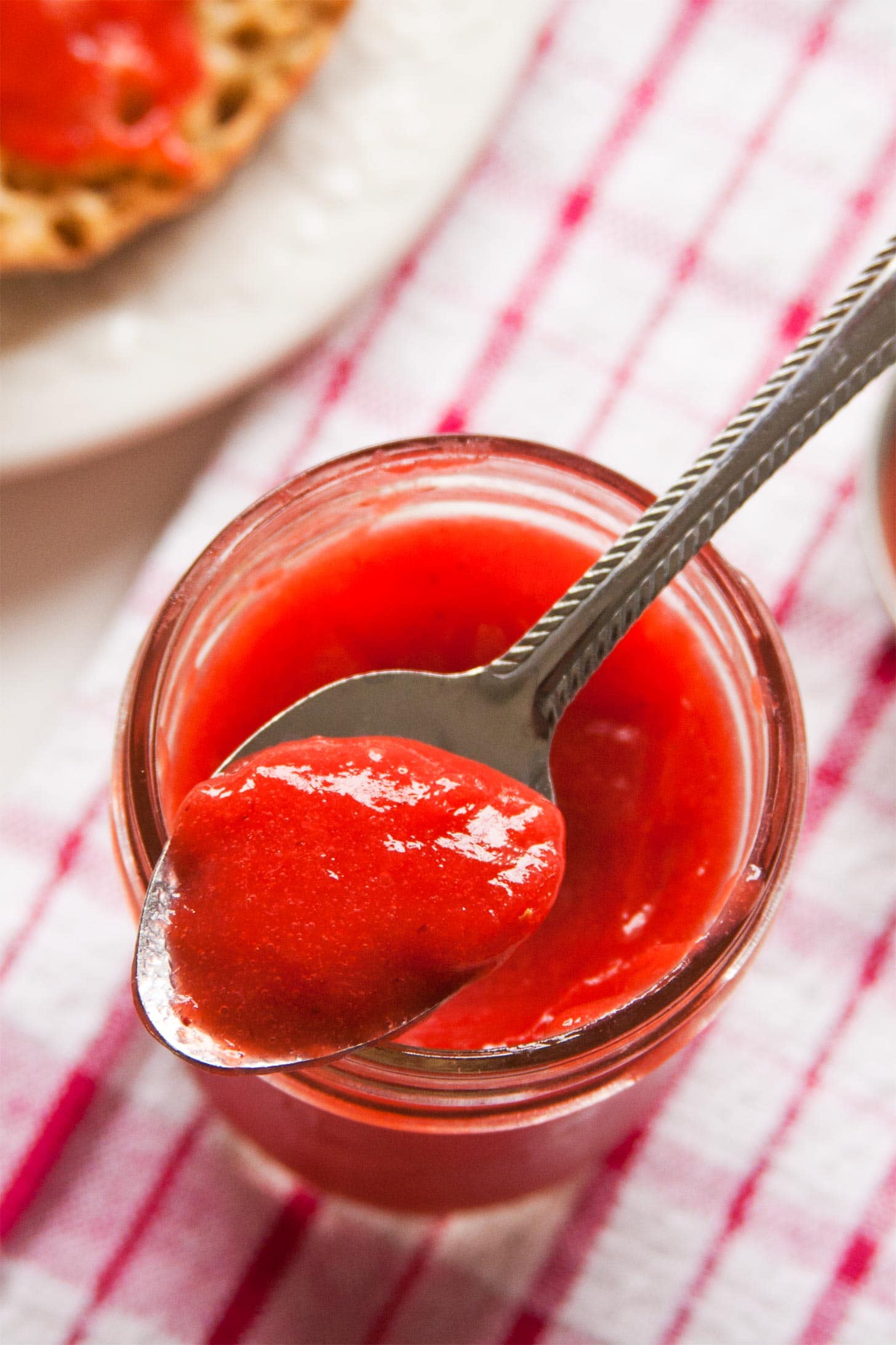 Spoon of strawberry curd resting on top of jar