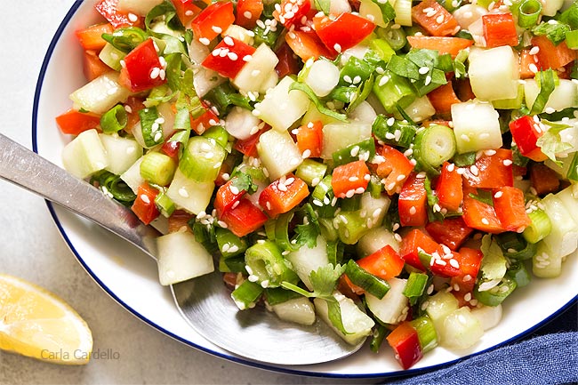 Close up of white bowl filled with green onion salad