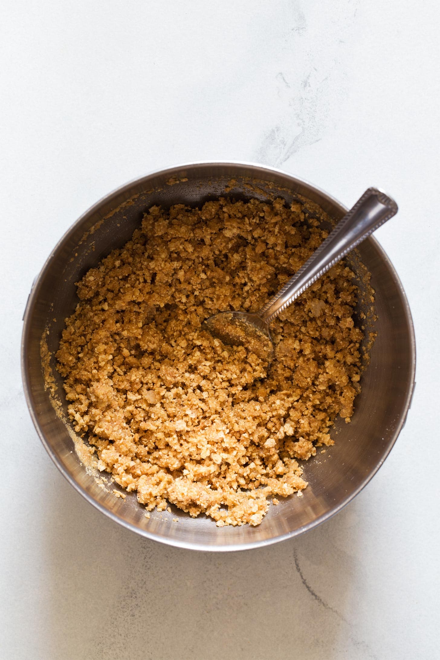 Mixing graham cracker crumbs with butter in a bowl