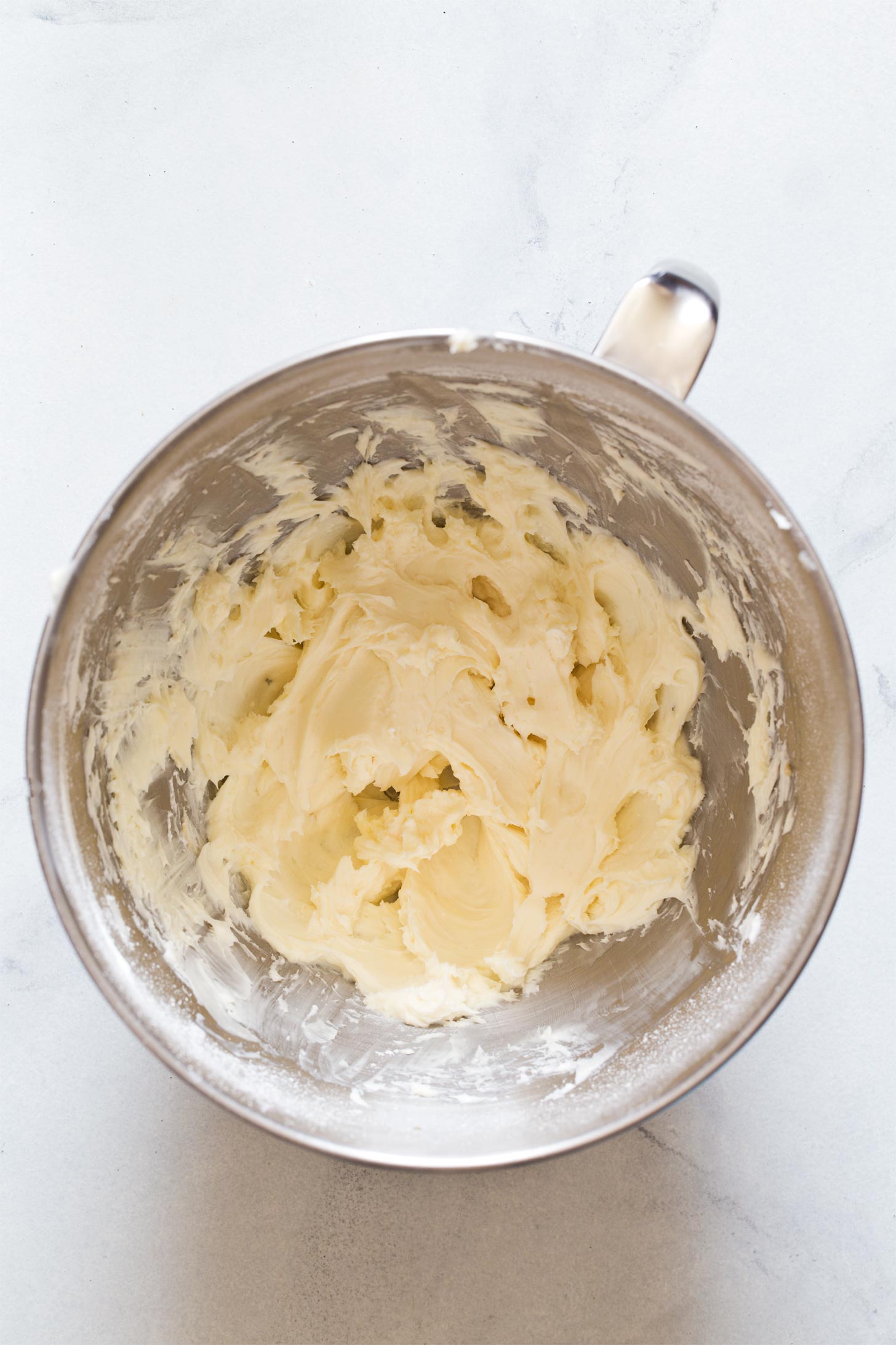 Beating together cream cheese and sugar to make cheesecake filling