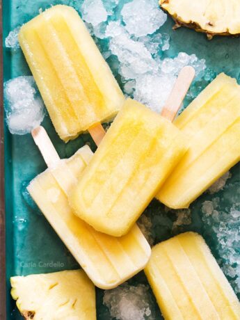 Pile of pineapple popsicles on a teal tray