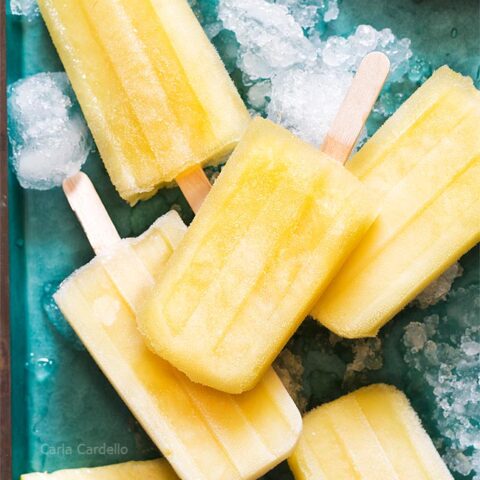Pile of pineapple popsicles on a teal tray
