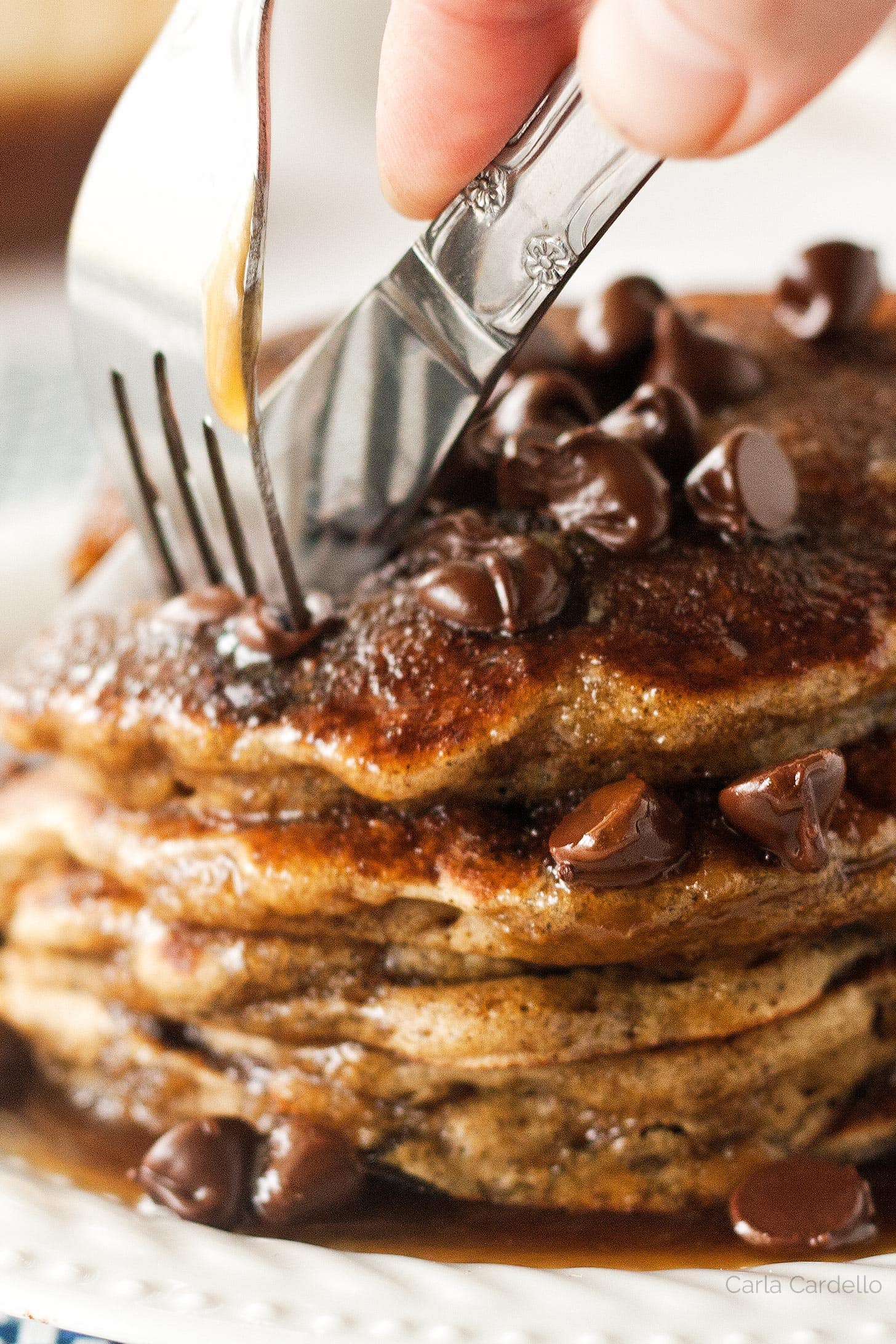 Fork and knife cutting chocolate chip pancakes