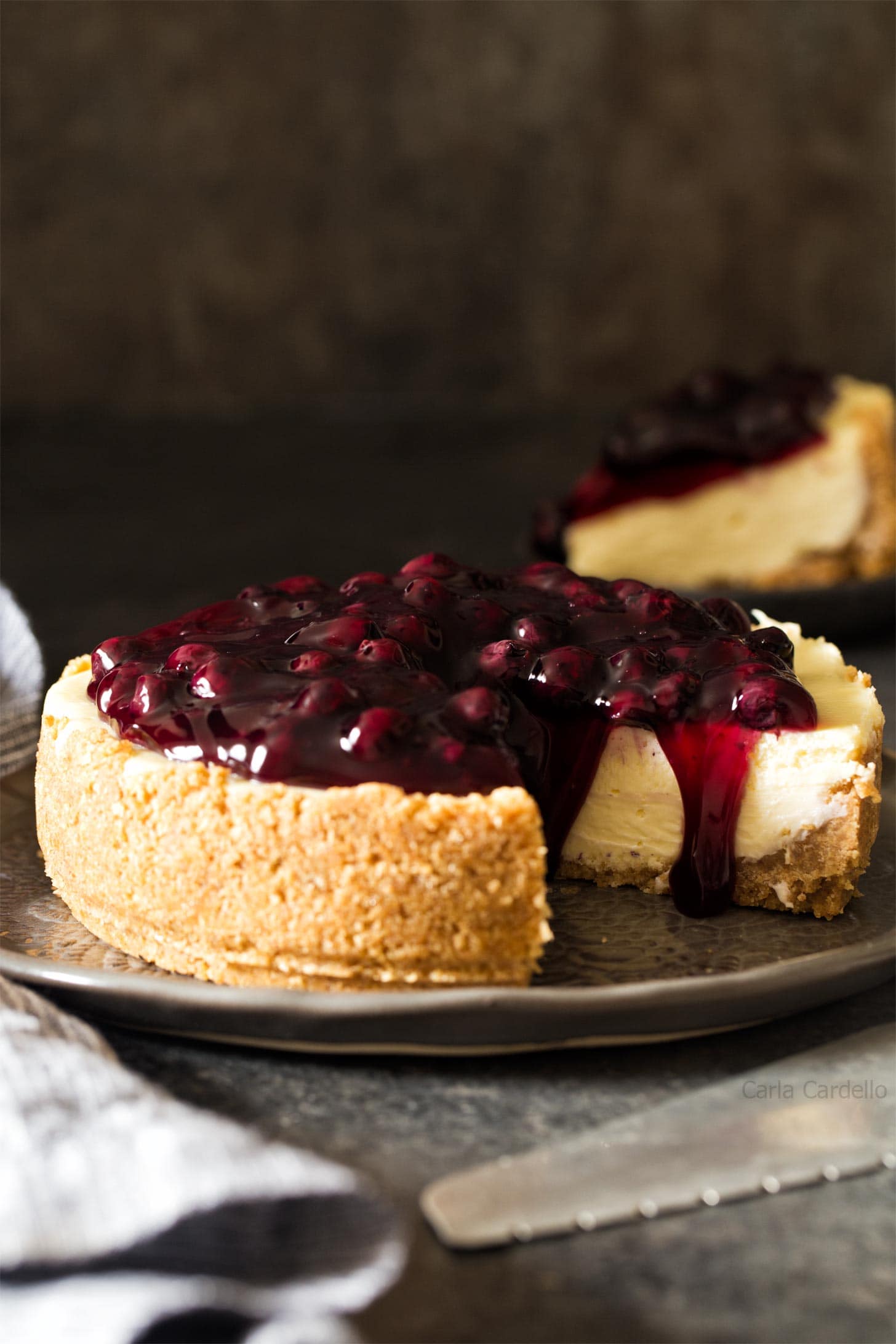 7 inch cheesecake with blueberry pie fililng on a gray plate
