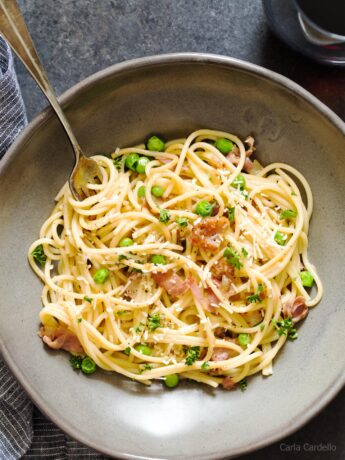 Close up of prosciutto pasta in grey bowl with fork