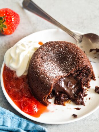 Mini Lava Cake oozing out onto plate with whipped cream and strawberry sauce