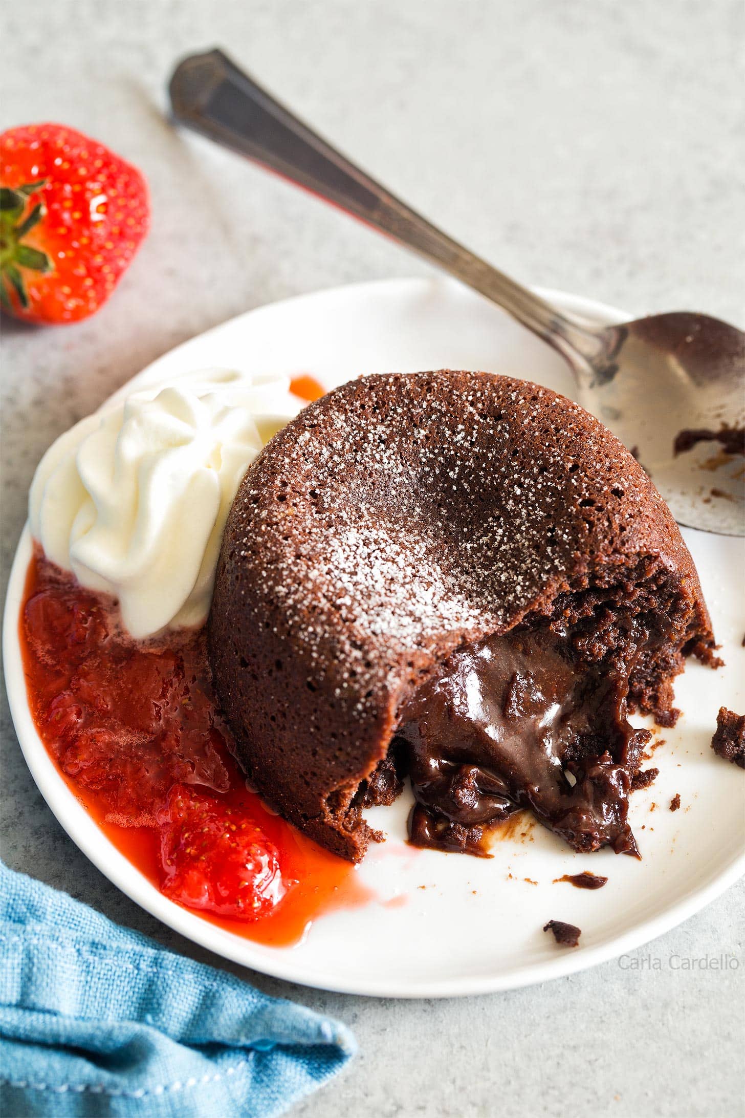 Mini Lava Cake oozing out onto plate with whipped cream and strawberry sauce