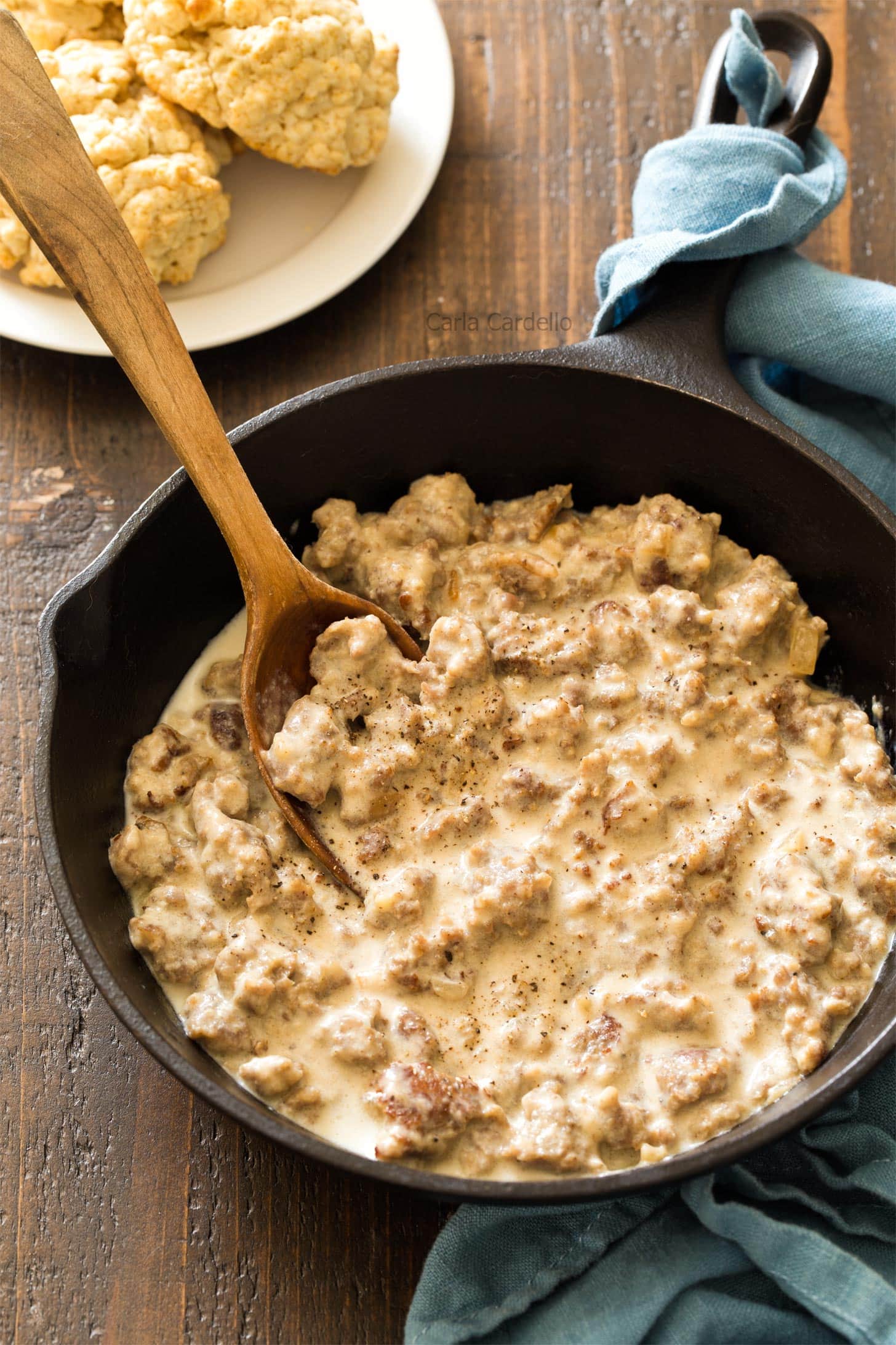 Sausage gravy in cast iron skillet with wooden spoon