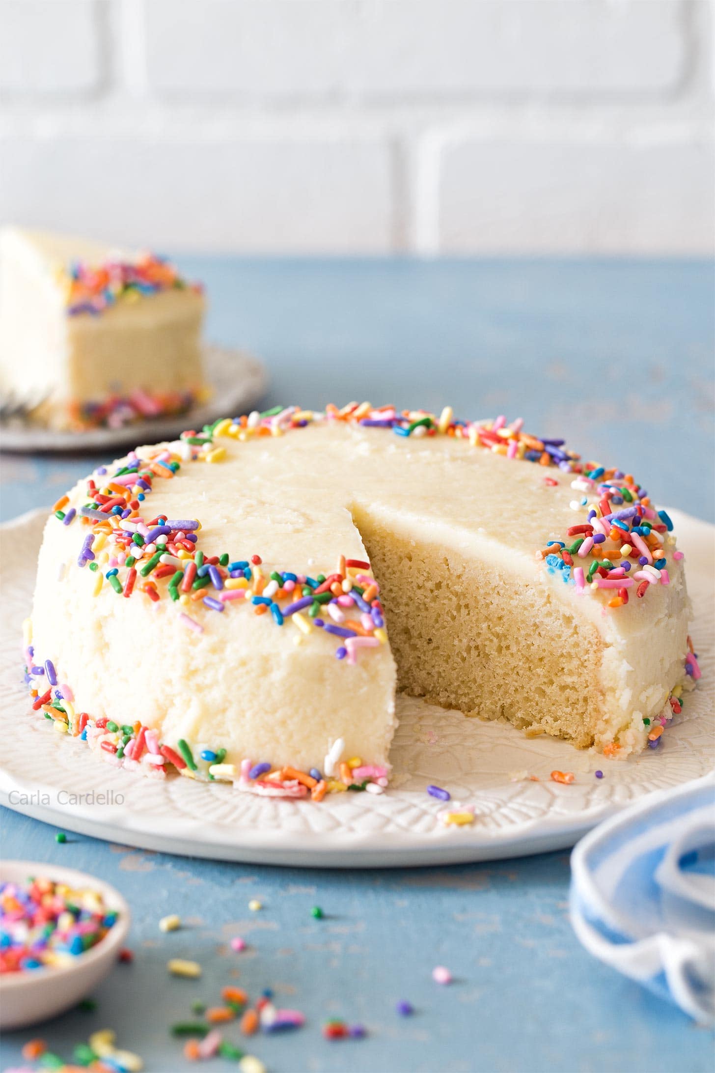 Small Vanilla Cake on white platter with blue table