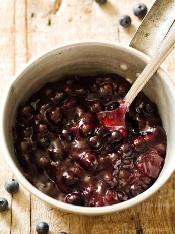 Blueberry pie filling in a saucepan with spoon