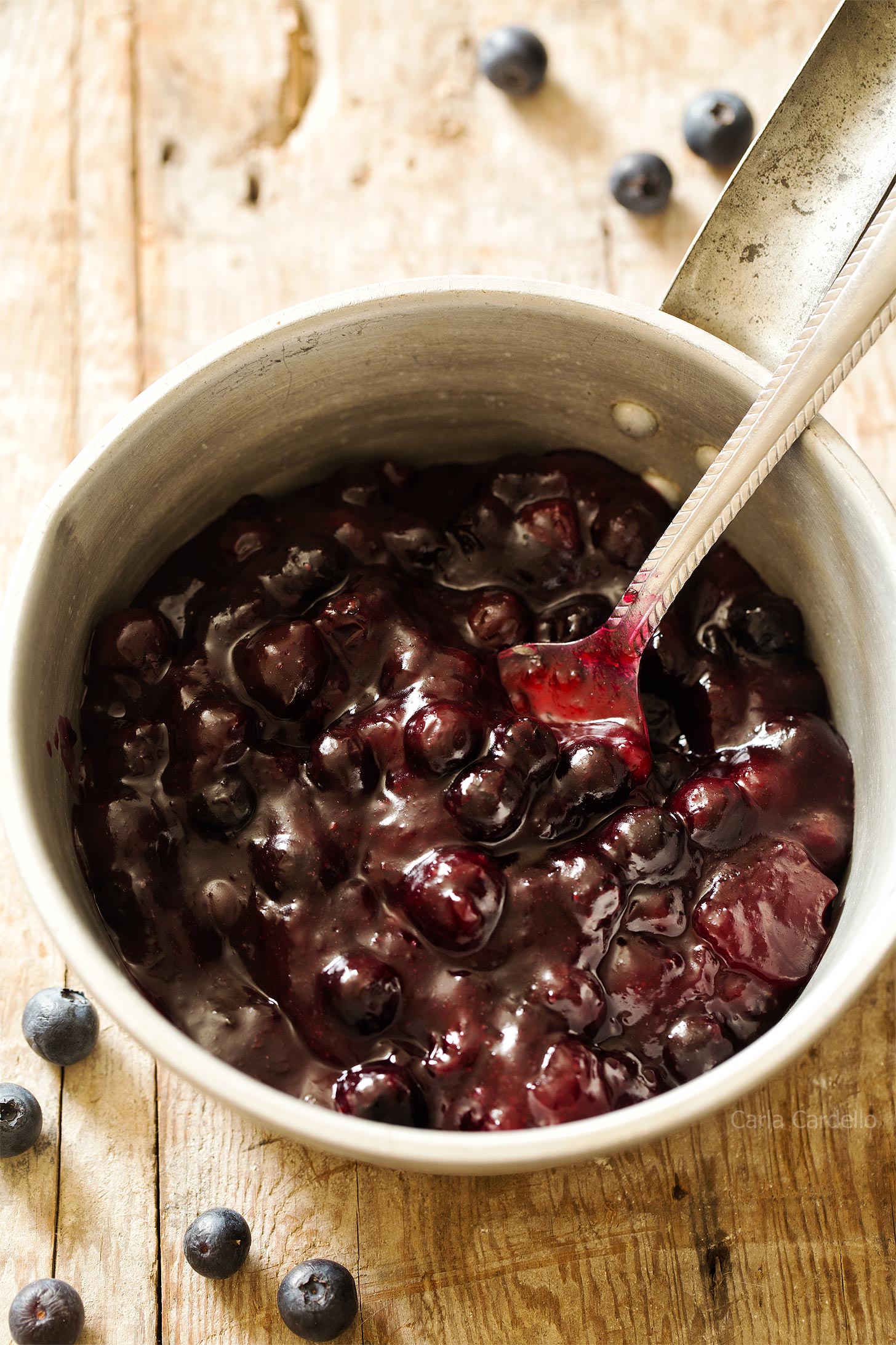 Blueberry pie filling in a saucepan with spoon