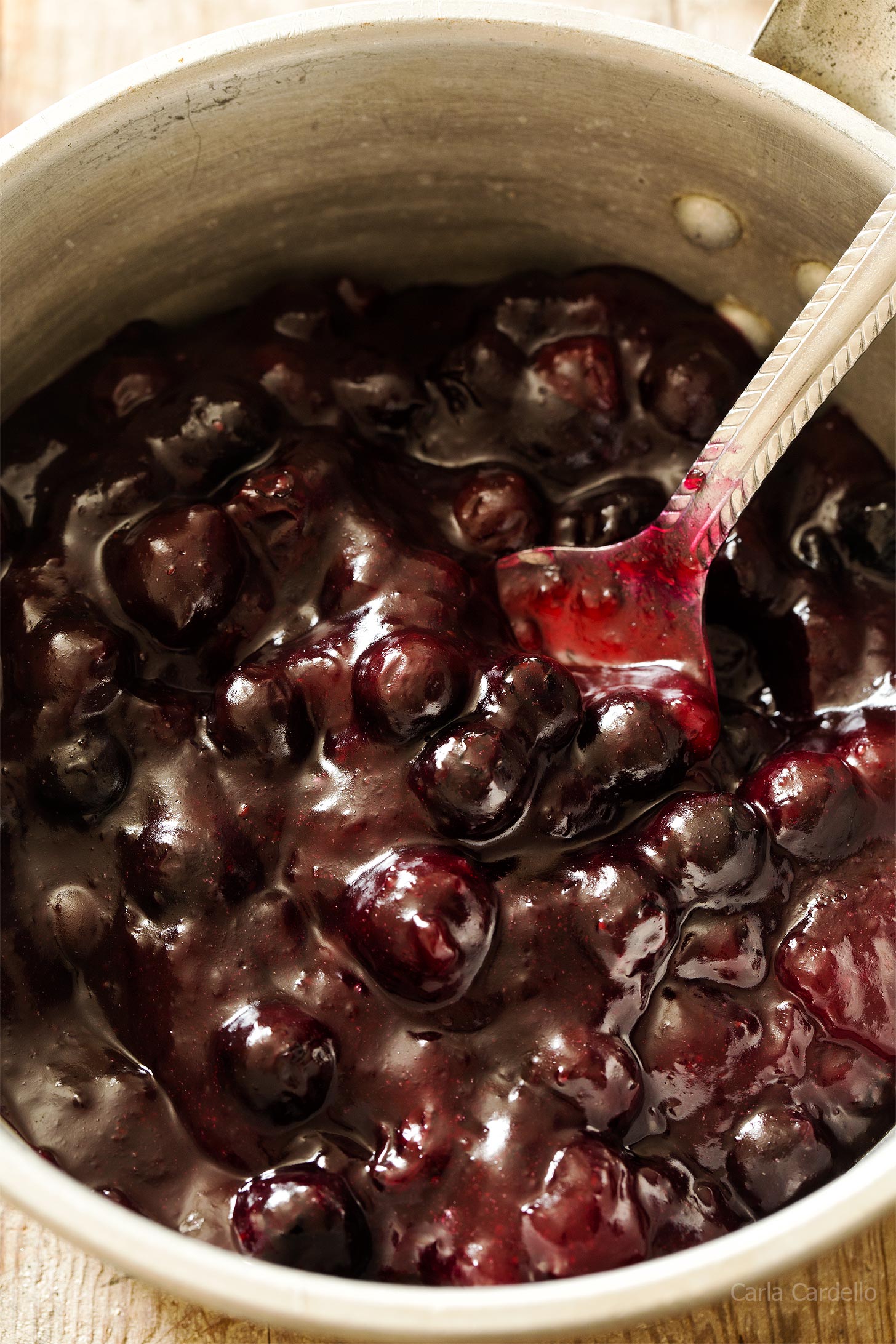 Close up of blueberry pie filling in saucepan with spoon