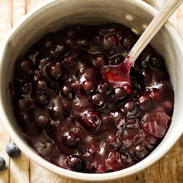 Blueberry pie filling in a saucepan with spoon