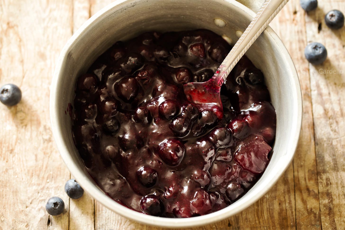 Blueberry pie filling in a saucepan with spoon