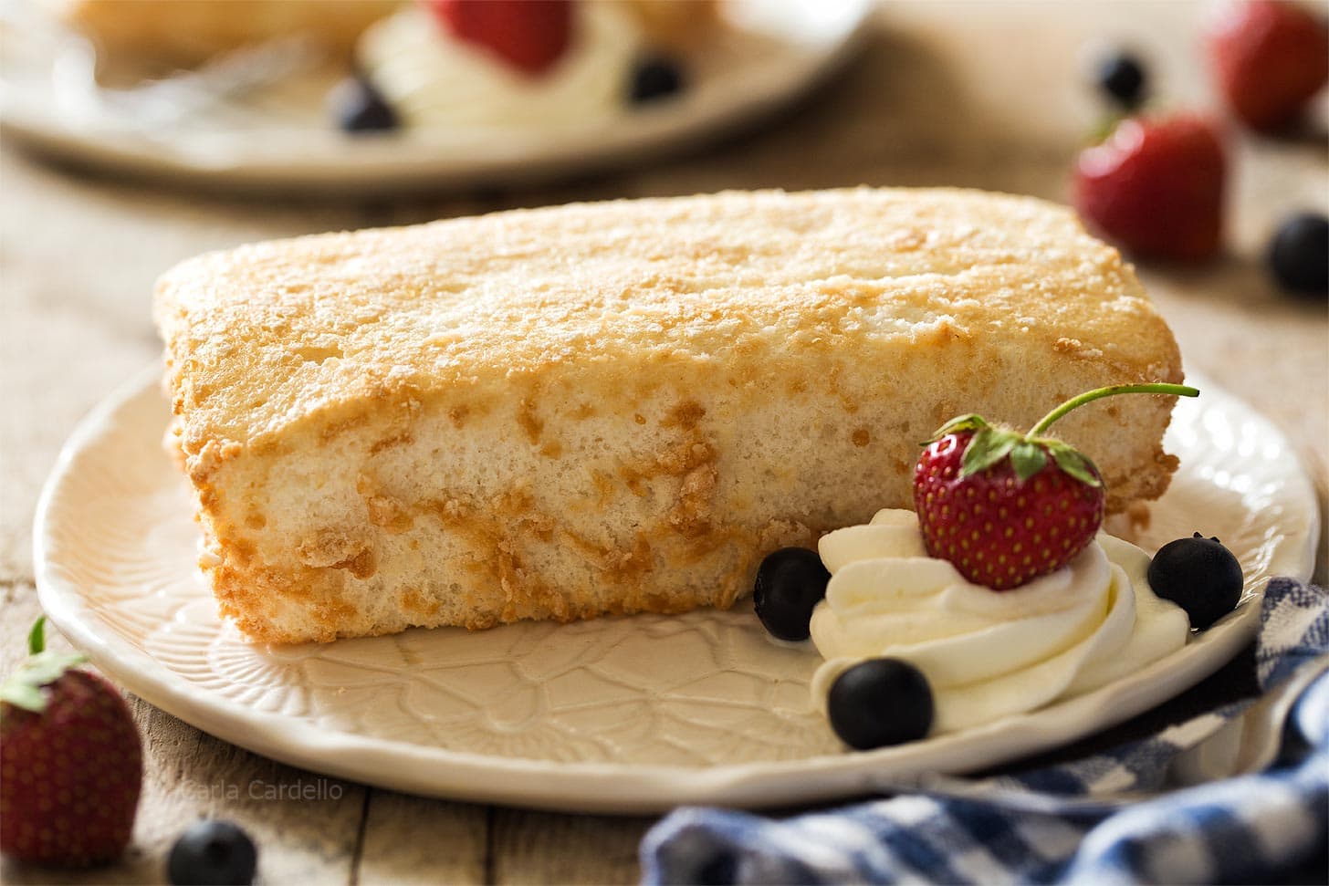 Mini Angel Food Cake on white plate with whipped cream and berries