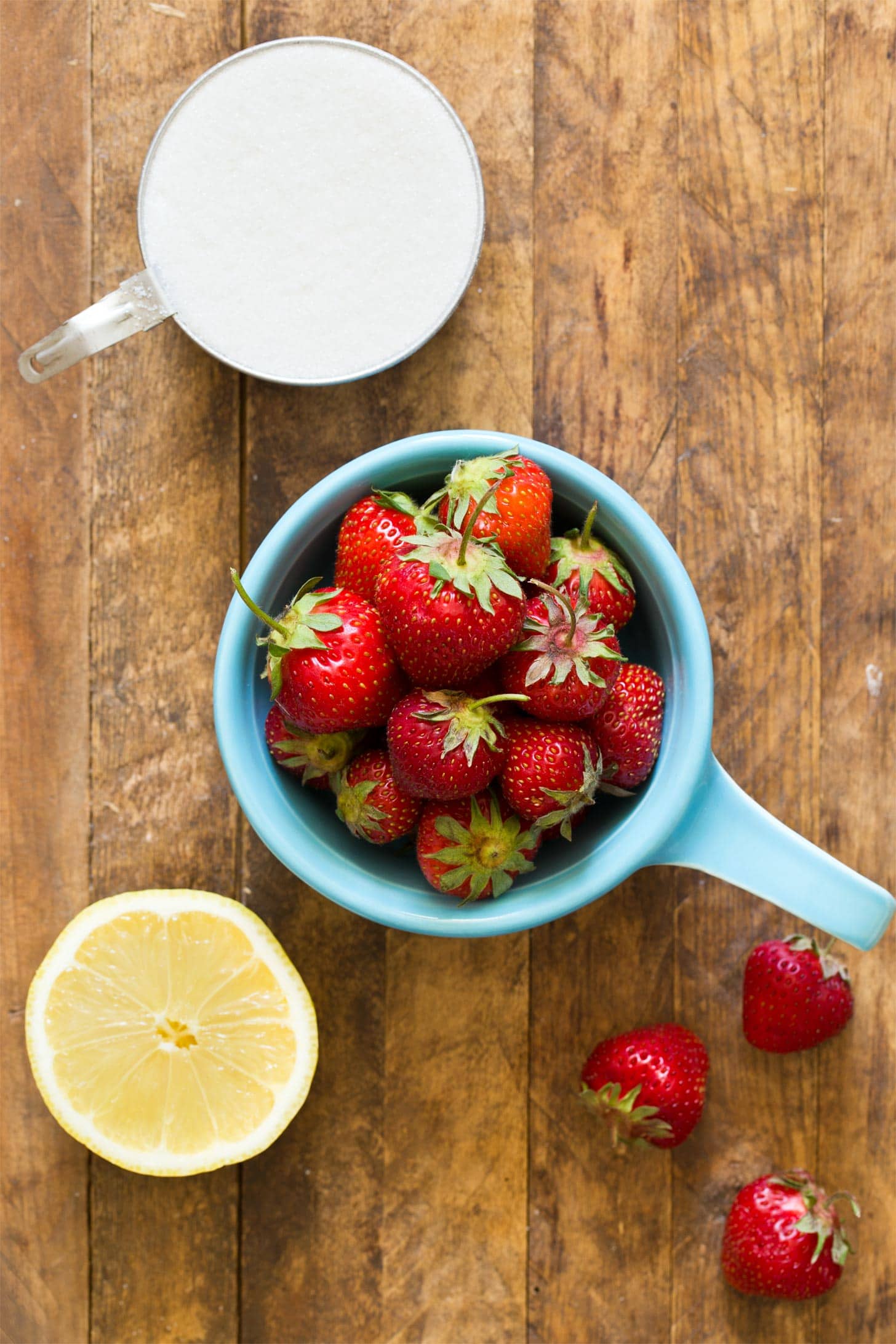 Strawberries, sugar, and lemon to make strawberry jam