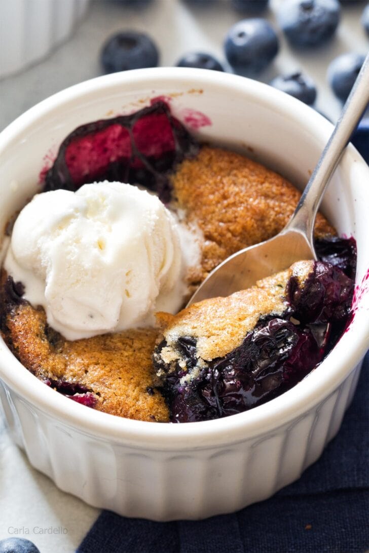 Close up of spoon serving blueberry cobbler