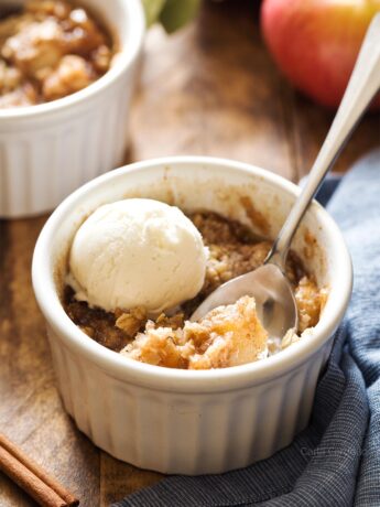 Apple crisp in white ramekin with spoon