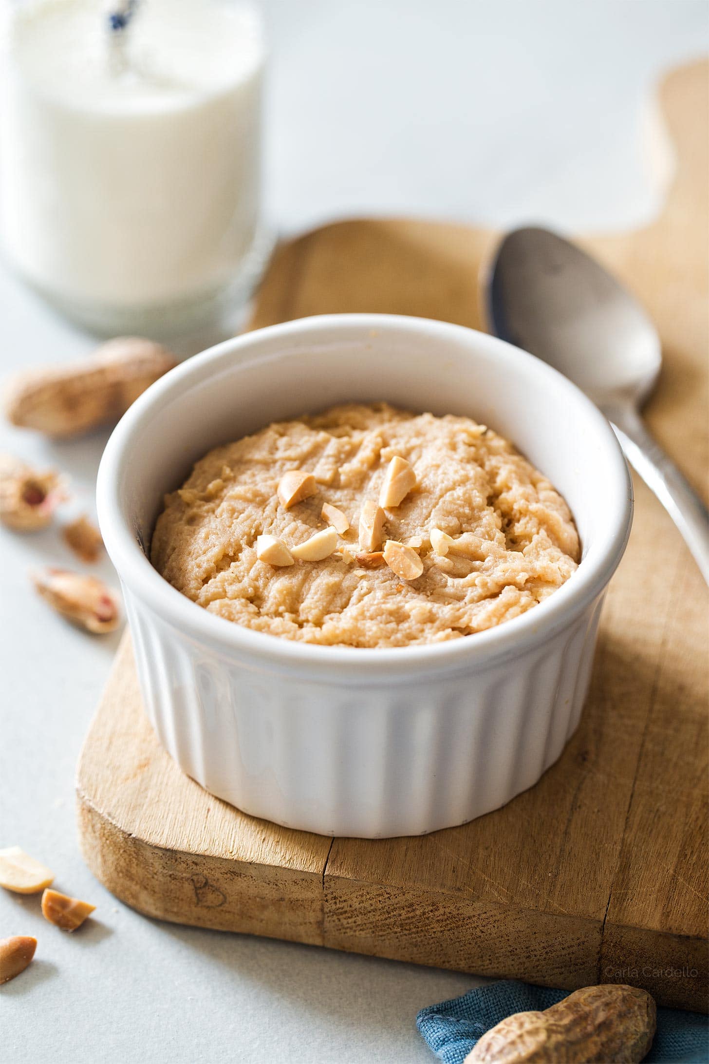 Microwave peanut butter cookie in a white ramekin on a wooden cutting board