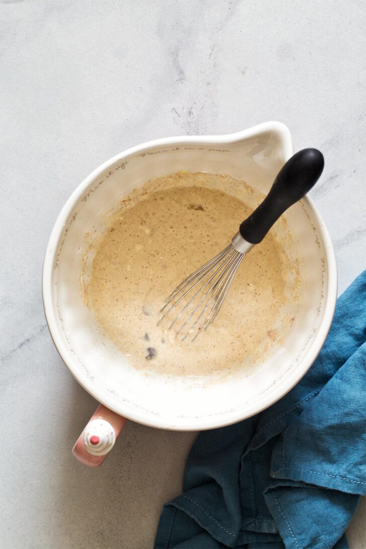 Chocolate chip pancake batter resting in mixing bowl with whisk