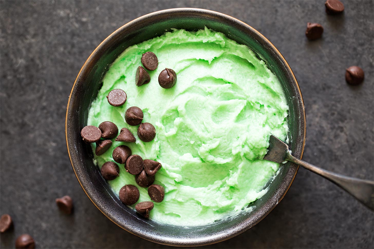 Mint buttercream frosting with knife in bowl