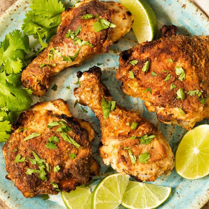 Air fryer fried chicken on blue plate with lime and cilantro