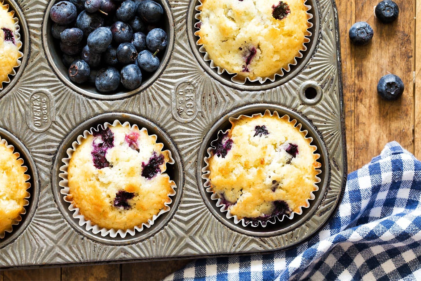 Close up of blueberry muffins in pan with fresh blueberries
