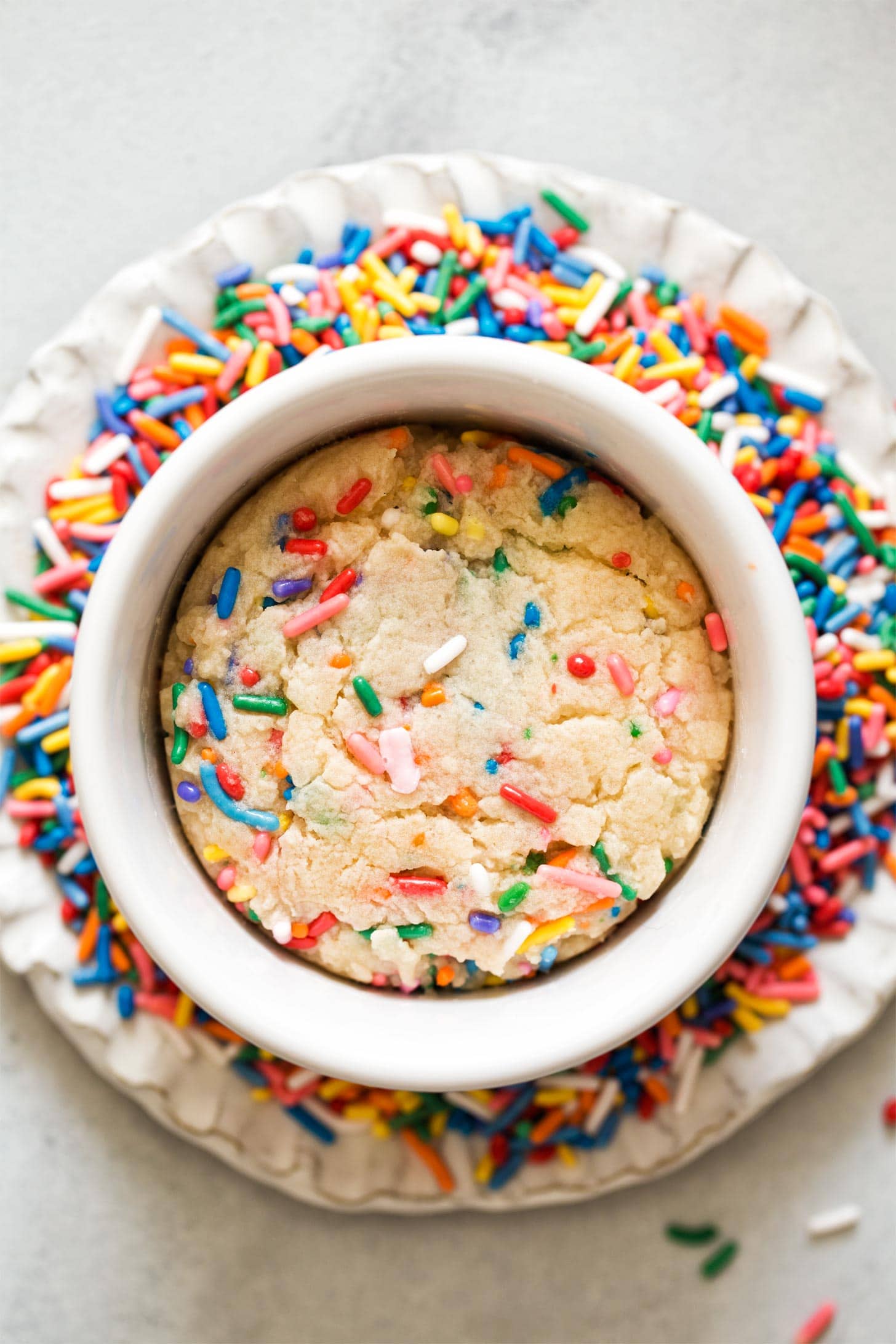 Overhead shot of sugar cookie for one on plate of sprinkles