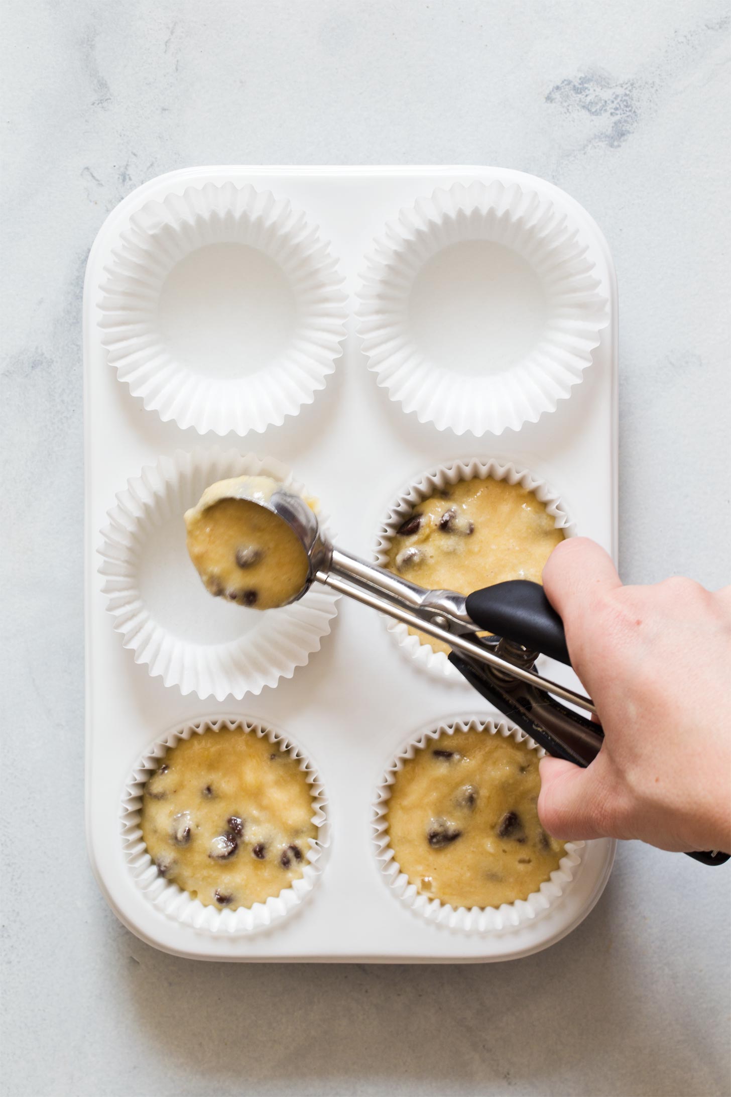 Scooping banana muffin batter in pan
