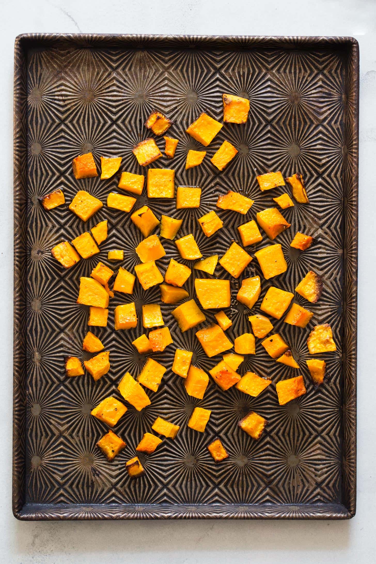 Roasted butternut squash cubes on a baking sheet