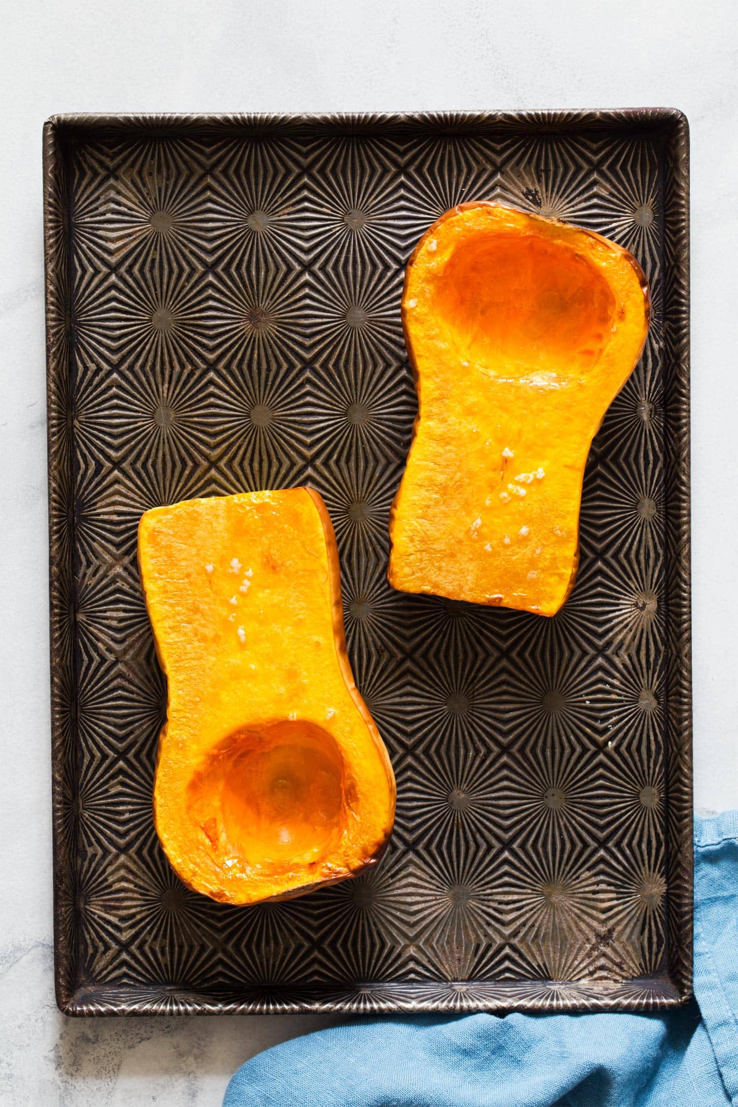 Oven roasted butternut squash halves on baking tray
