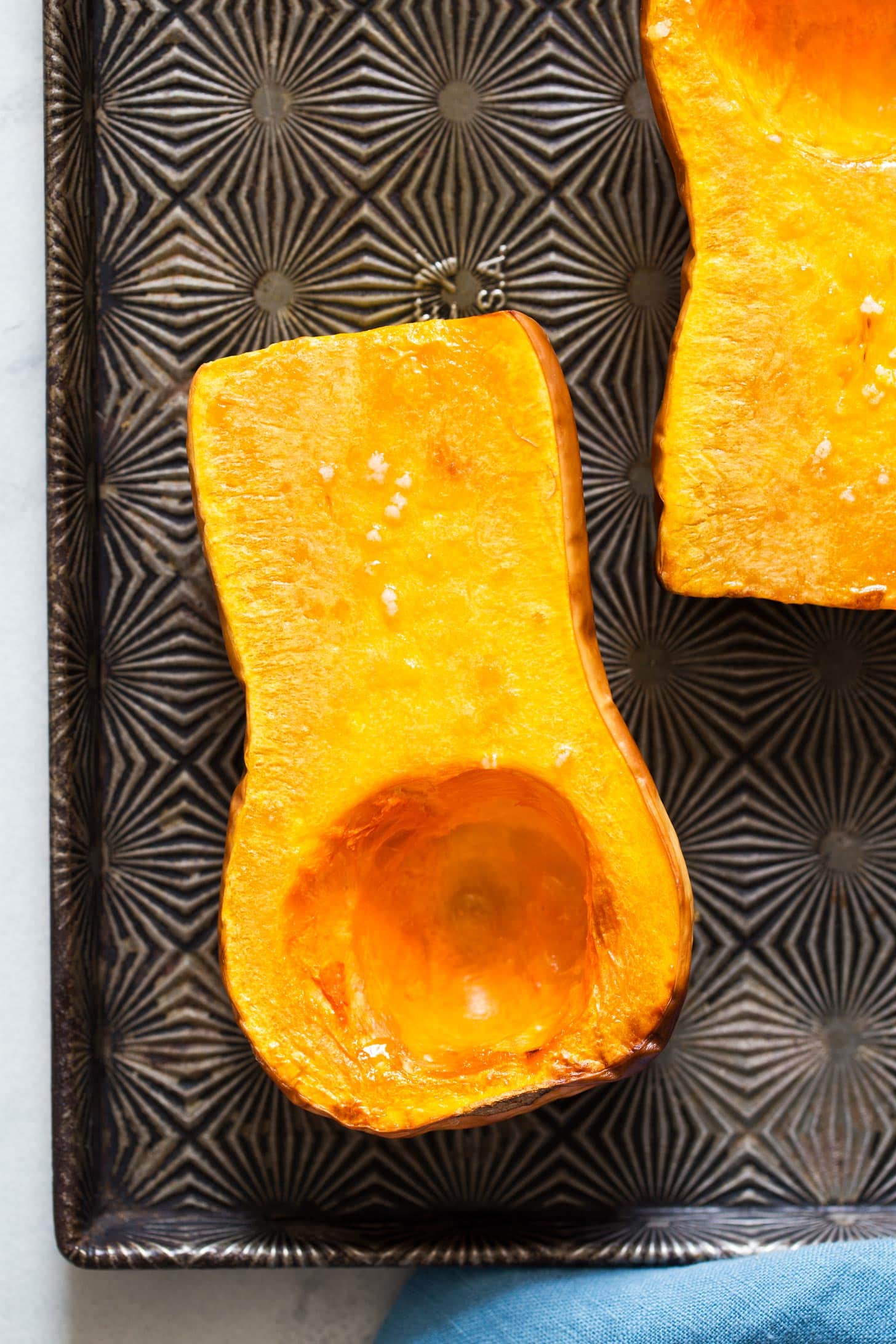 Close up of roasted butternut squash halves on a baking tray