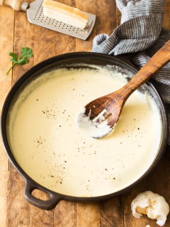 Homemade Alfredo Sauce made in a skillet with wooden spoon