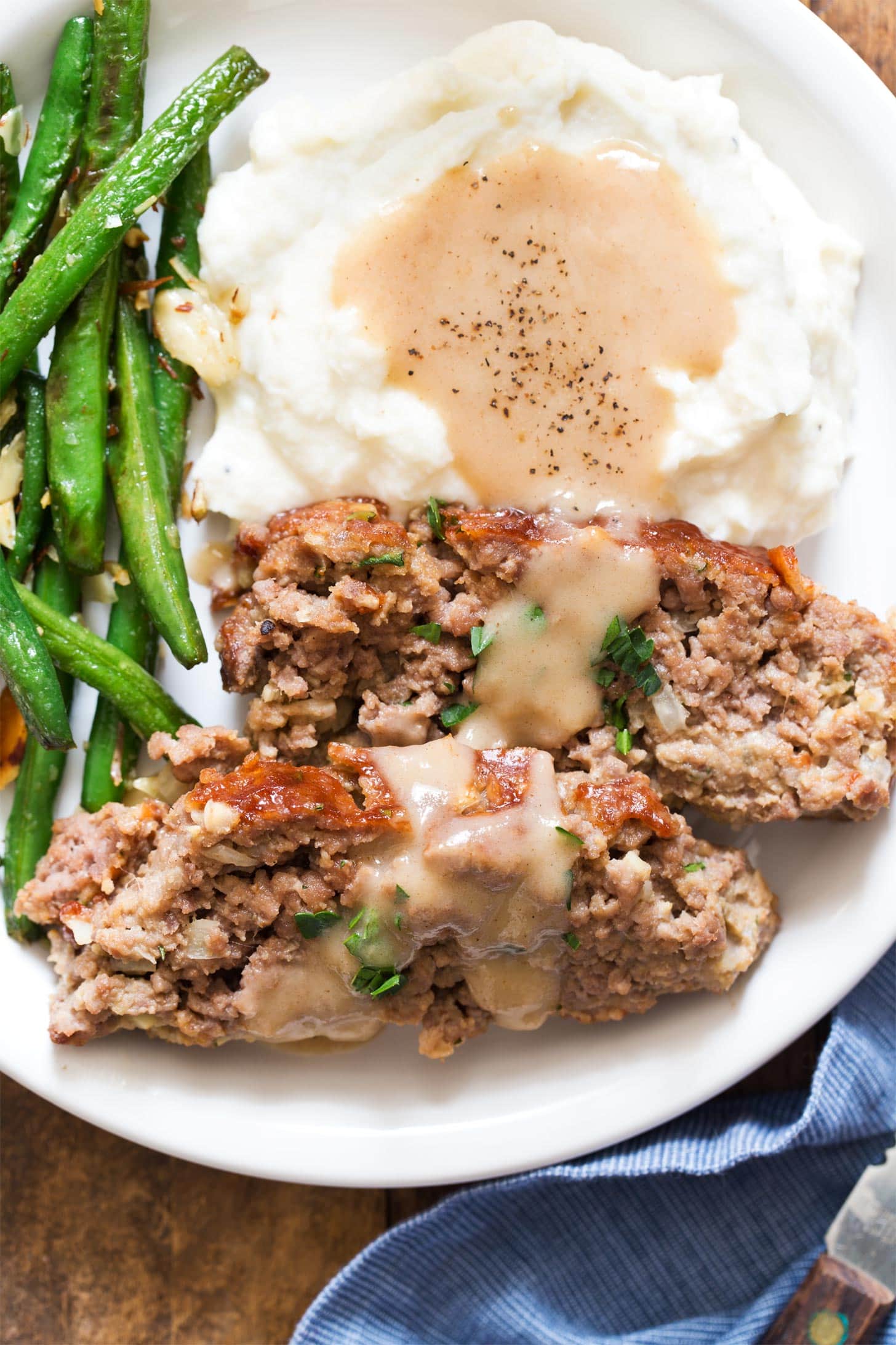 Close up of meatloaf for two with mashed potatoes, gravy, and green beans