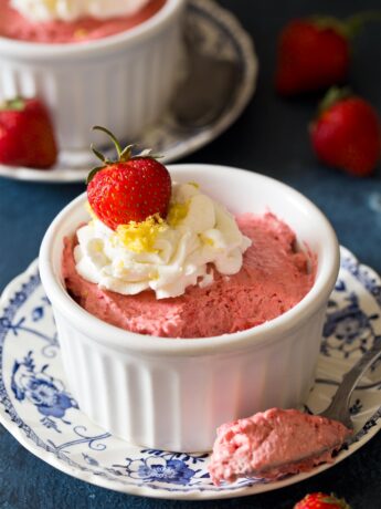 Strawberry mousse in a ramekin with spoon taking a bite