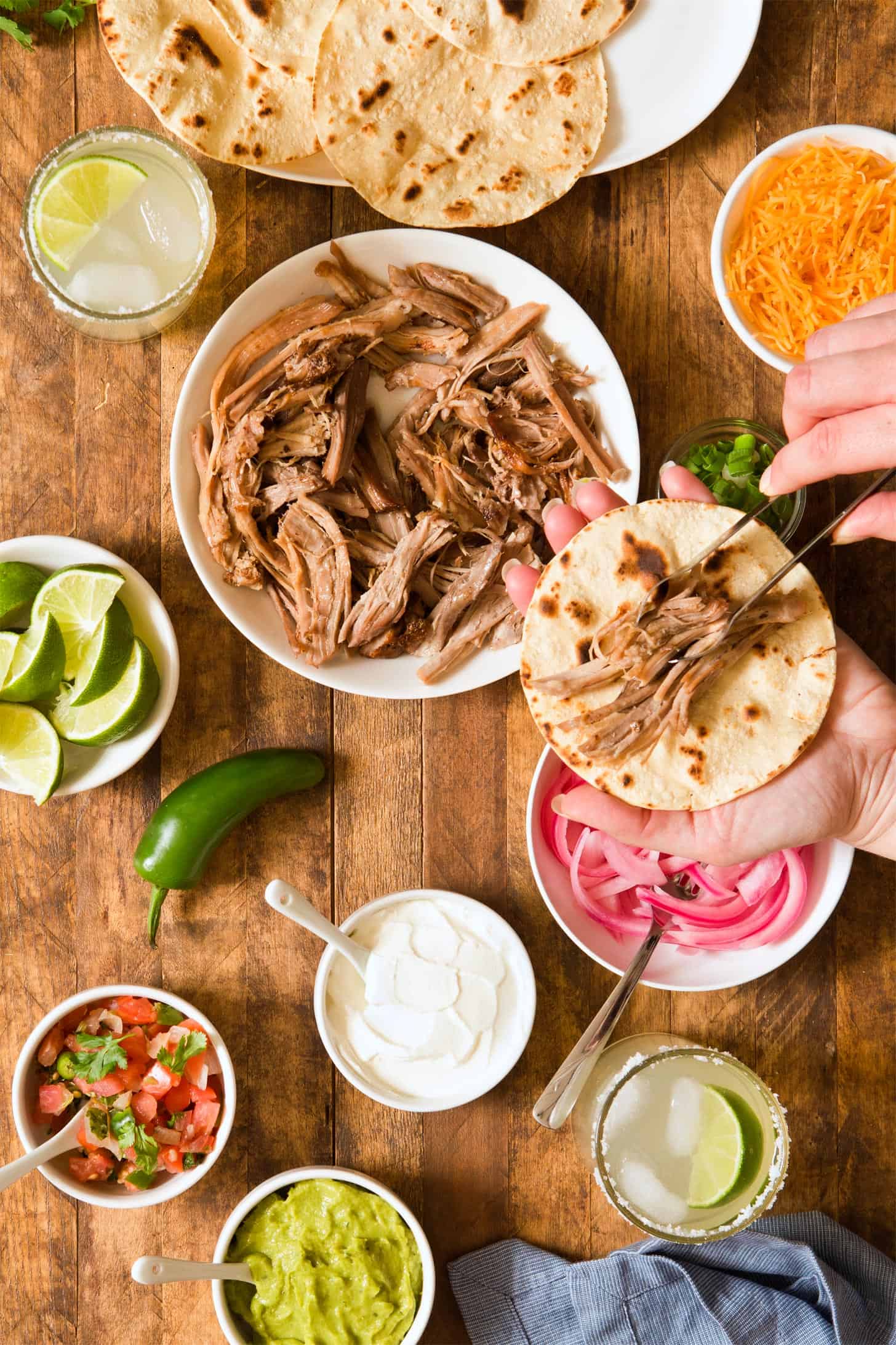 Adding pork carnitas to corn tortilla to make tacos